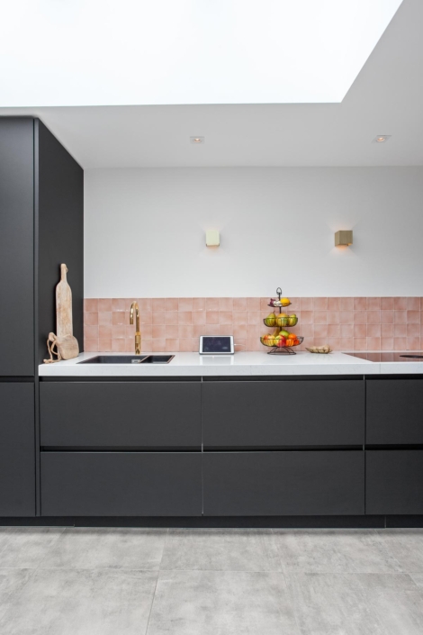Strakke zwarte keuken met roze tegel