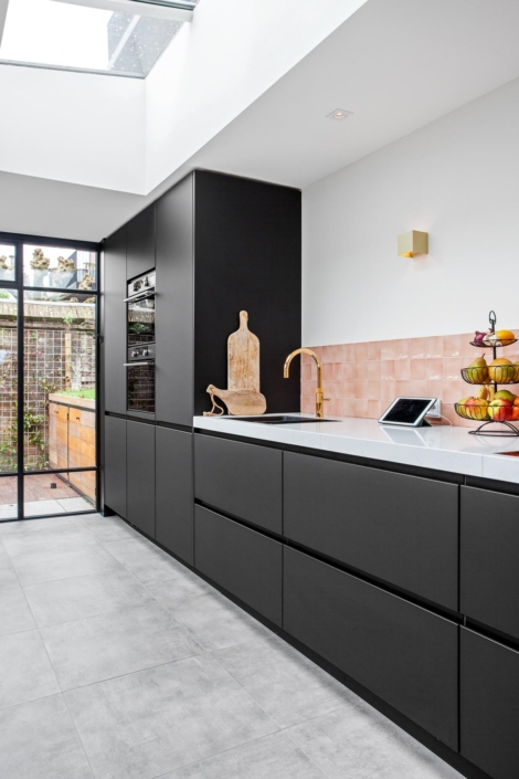 Strakke zwarte keuken met roze tegel